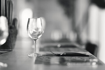 An empty wine glass placed on a table in a fancy restaurant with a knife and a fork next to it