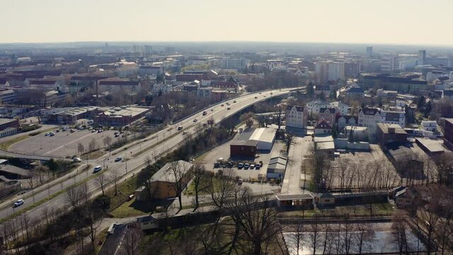 An aerial view of Cottbus in Brandenburg. The sun is shining and cars are driving on an motorway through the city. You can see many old and new houses on the skyline of Cottbus.