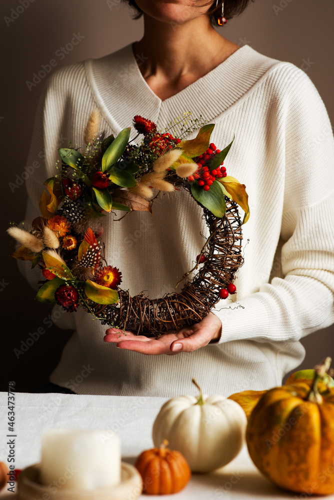 Wall mural Woman hands with diy floral autumn wreath with driad grass, plant and berry