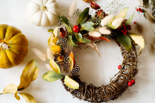 Flat lay with diy floral autumn wreath with driad grass, plant and berry