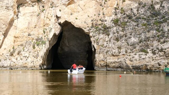 Boat with tourists go inside cave at Inland sea, Gozo
