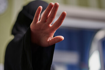 A Muslim woman in traditional black clothing nikab showing stop hand gesture. Role of women in...