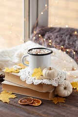 Obraz na płótnie Canvas Autumn composition with hot chocolate with marshmallow. Aromatherapy on a grey fall morning, atmosphere of cosiness and relax. Wooden background, window sill, close up
