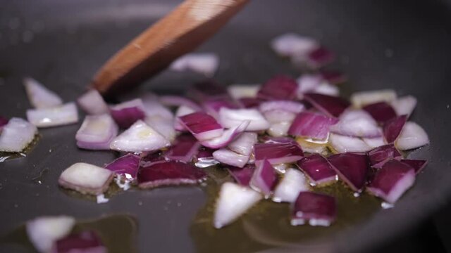 mixing chopped onion on frying pan with wood spoon slow motion