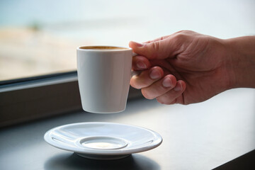 Close up of a young caucasian man hand holding a cup of coffee.