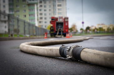 Against the background of a blurred fire truck, a fire hose is stretched out.