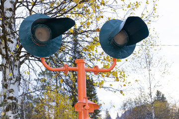 Railway traffic light or semaphore at a railway crossing against autumn forest background