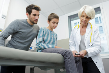 Fototapeta premium senior female therapist examining boy with reflex hammer