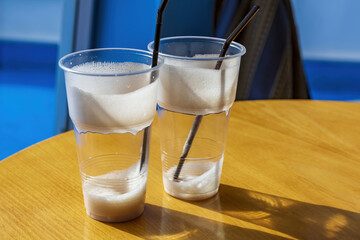 Used plastic cups with straws with leftover milkshake foam