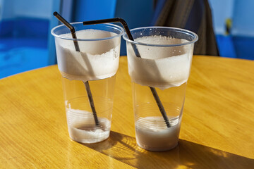 Used plastic cups with straws with leftover milkshake foam