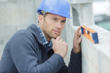 worker in overalls measures the wall with a level