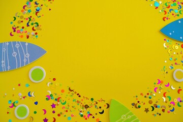Invitation for a birthday or a beach party consisting of several fish and bubbles surrounded by confetti and sequins on a yellow background