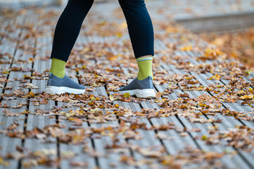 close-up of a female legs on wooden walking trails covered with autumn leaves