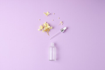 Minimal composition with cosmetic bottle with flowers on rose background. Flat lay, copy space