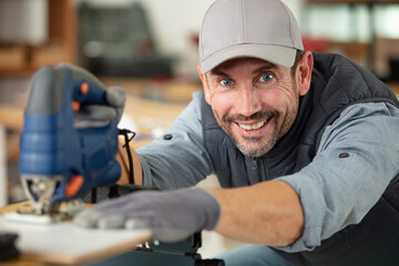 cheerful man using electric jigsaw