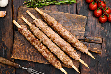 Turkish  meat kebab, on serving board, on old dark  wooden table background, top view flat lay