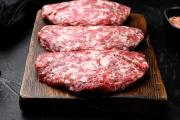 Raw meat, cutlet, on black dark stone table background