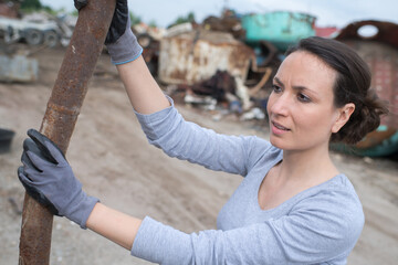 woman moving metal bar in scrap yard