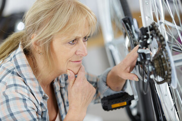Fototapeta na wymiar happy positive woman master repairing bicycle in workshop