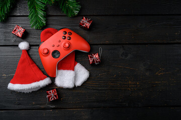 Joystick gaming controller with Christmas decoration, on black wooden table background, top view...
