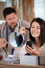 man looking at wristwatch while woman putting powder