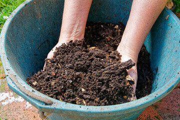 A bucket of compost being hand mixed.