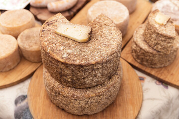 Wheels of crafted natural cheese at the market stall, a piece of artisan cheese is lying on the wheel, cheese are produced by farmers, cheese produced in traditional way, food for breakfast and picnic
