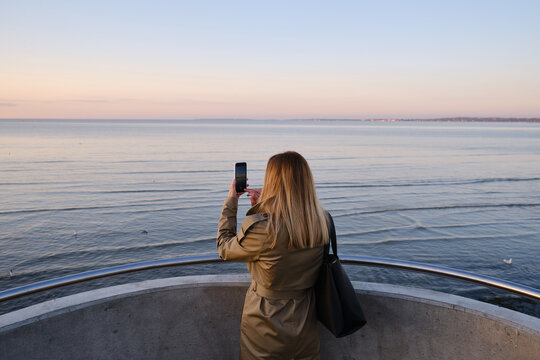 The girl holds a smartphone in her hands and takes pictures of the sea. Focus on the phone screen. Make memories using your smartphone. Mobile phone close up