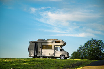 Closeup shot of a camper van parked in the green field under the blue sky