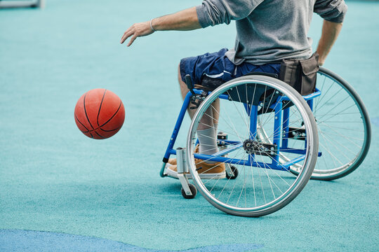 Close-up of sportsman with disability sitting in wheelchair playing basketball outdoors