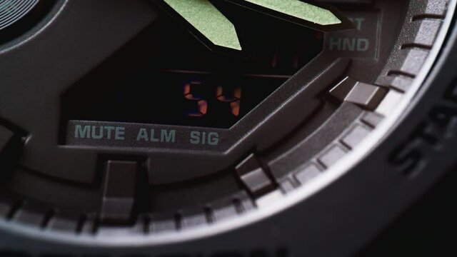 The minute hand moves on the black watch and the numbers on the dial change in close-up