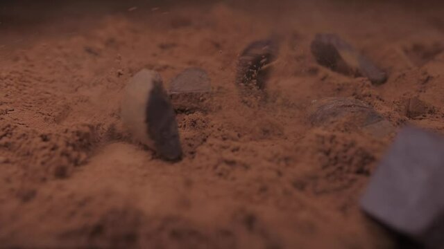 raw chocolate falling into cacoa powder slow motion