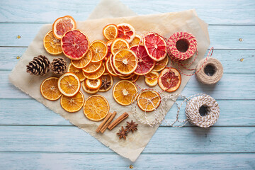 cinnamon, anise, dried oranges and grapefruit slices, threads for diy projects, gift wrapping and beautiful eco Christmas decorations like wreaths arranged on a blue wooden table - 463489108