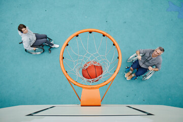 High angle view of couple with disability playing basketball together in wheelchairs