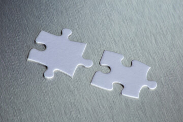 connection. 2 white jigsaw tiles about to fit together. aluminium background. technological background.