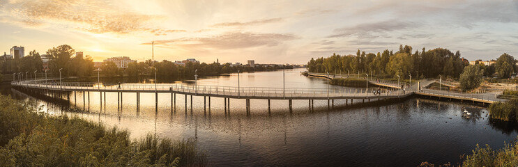 Fototapeta premium The embankment of Lake Kaban in Kazan. A beautiful modern promenade in the city. A beautiful pedestrian bridge over the lake. Modern urban landscaping 