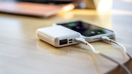 A smartphone is charged from a small white power bank.