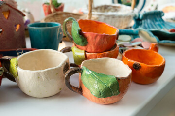 Multi-colored handmade ceramic bowls and cups covered with glaze in the pottery workshop