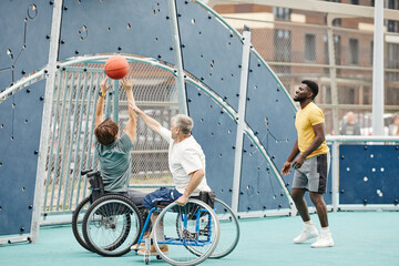 African sportsman playing basketball outdoors together with couple with disability
