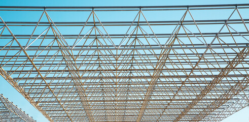 Openwork metal construction on a blue sky background on a clear sunny day, texture backgrounds for graphic design. Abstract wallpaper.