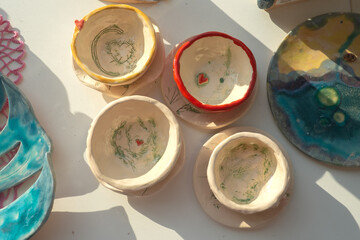 Multi-colored handmade ceramic bowls and cups covered with glaze in the pottery workshop