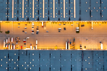 Aerial view of cars waiting to be unloaded at the logistics warehouse, night view of the industrial...