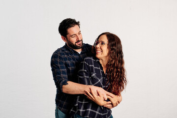 An adult couple in plaid shirts showing thumbs up to the camera and smiling against a white background - 463492975