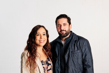 An adult couple in plaid shirts showing thumbs up to the camera and smiling against a white background - 463492976