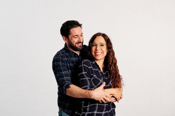 An adult couple in plaid shirts showing thumbs up to the camera and smiling against a white background - 463492988