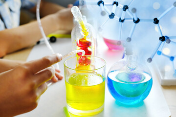 two children 7-9 years old, elementary school boys, do chemical experiments, pour colored liquids into glass flasks, mix colors, school education concept, hands-on study of chemistry