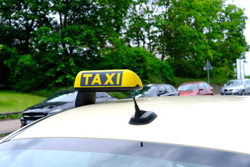 white passenger car with a yellow taxi sign on the roof at the top is waiting for its client,...