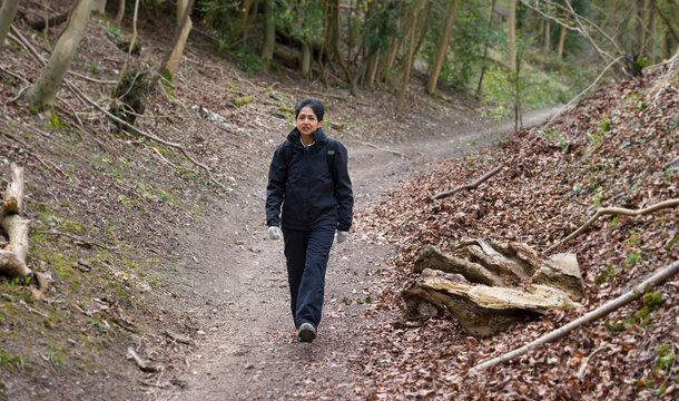 Asian Indian Woman Hiking In UK Forest In Winter