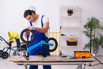 Young male repairer repairing bike indoors