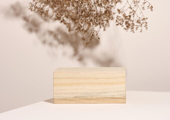 wooden podium to showcase cosmetics and other items, beige background with dry wildflowers and shadow